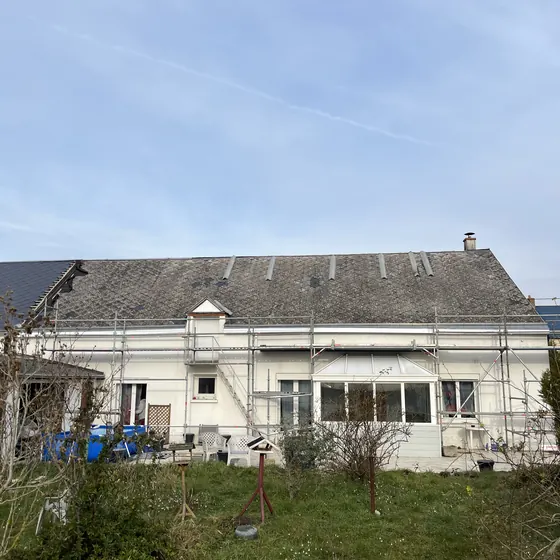 Couverture refaite sur une longue maison basse, échafaudage en façade